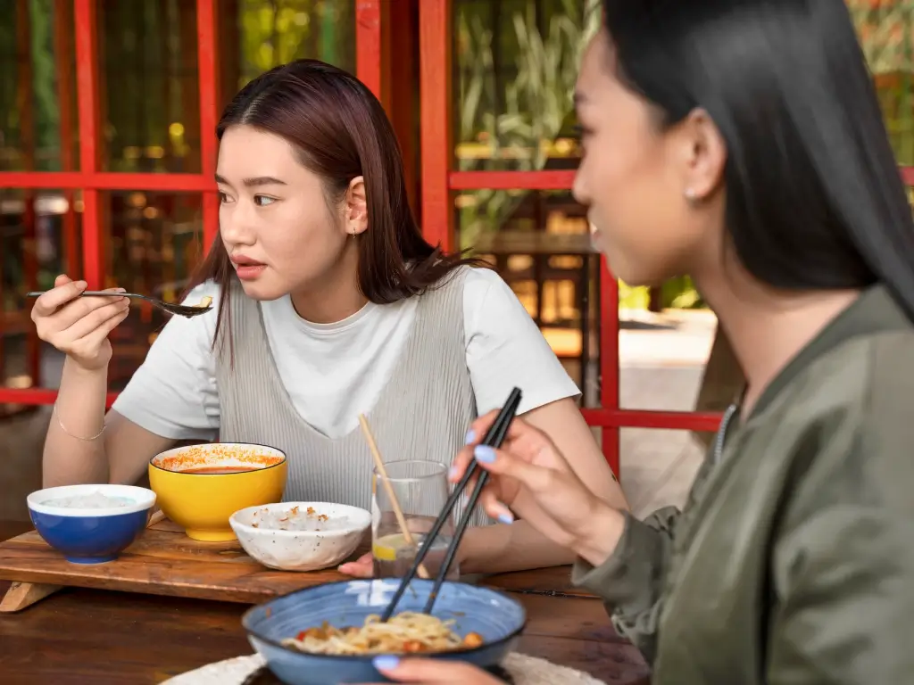 two women eating Singapore noodles 