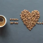 A cup of coffee with a heart cardiogram on a black table shows if is coffee good for your heart or not.