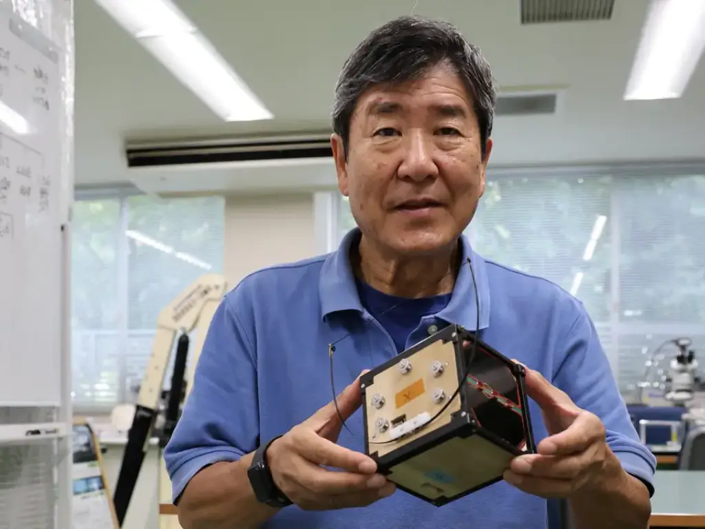 Former Japanese astronaut and Kyoto University professor Takao Doi holds a model of the wooden satellite LignoSat in his Kyoto lab during a Reuters interview.